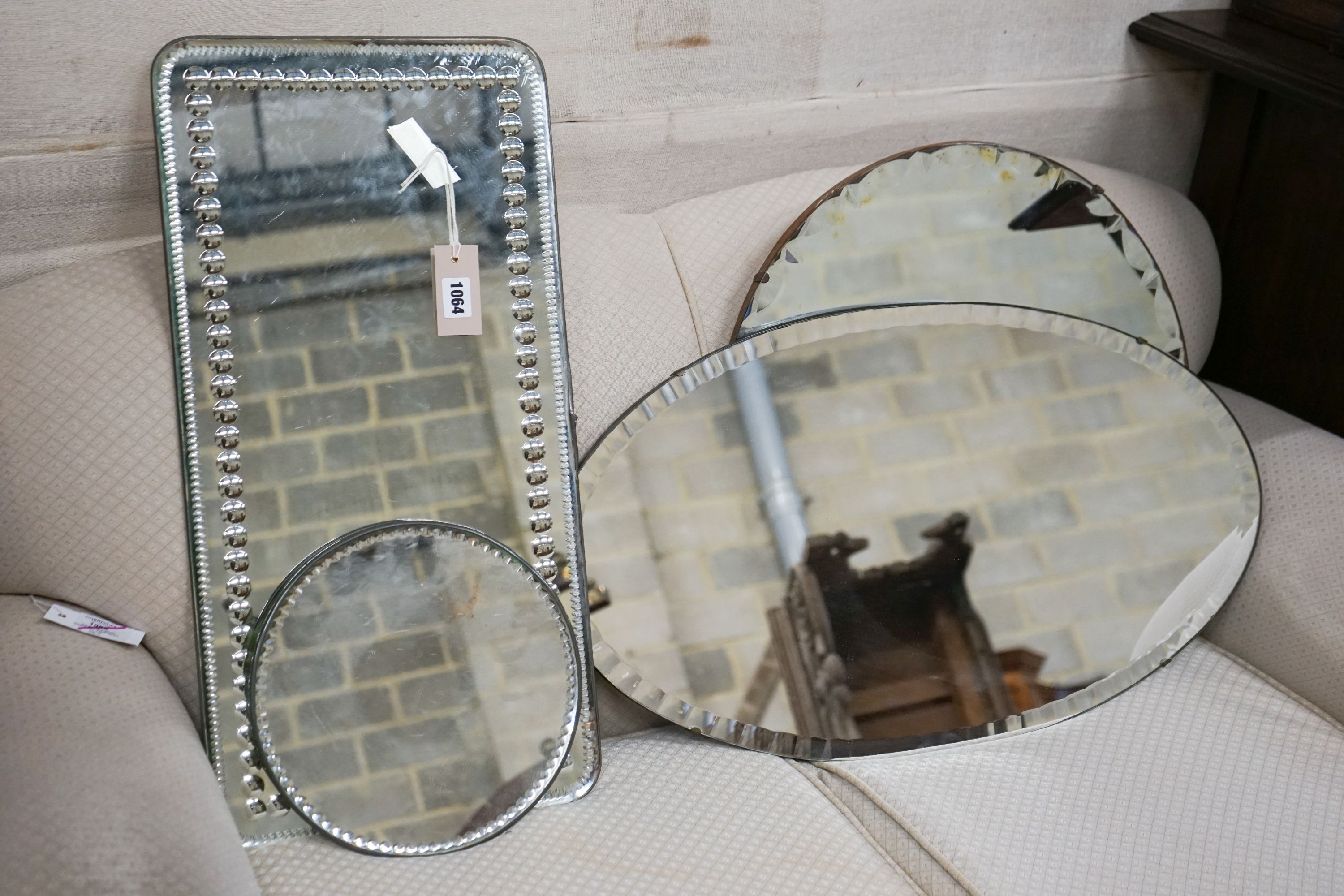 An oblong mirror, circular mirror, oval mirror and a mirrored table plateau, all frameless, largest 68cm, height 39cm